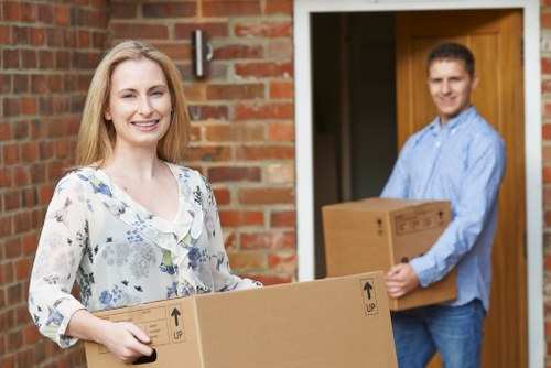 Movers carrying furniture through a narrow apartment corridor in Queenspark